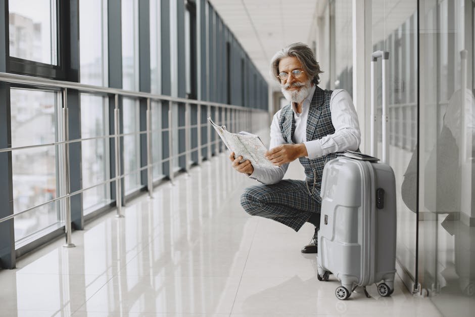 Senior man in airport hallway holding a map, sitting beside luggage, illustrating travel and exploration.